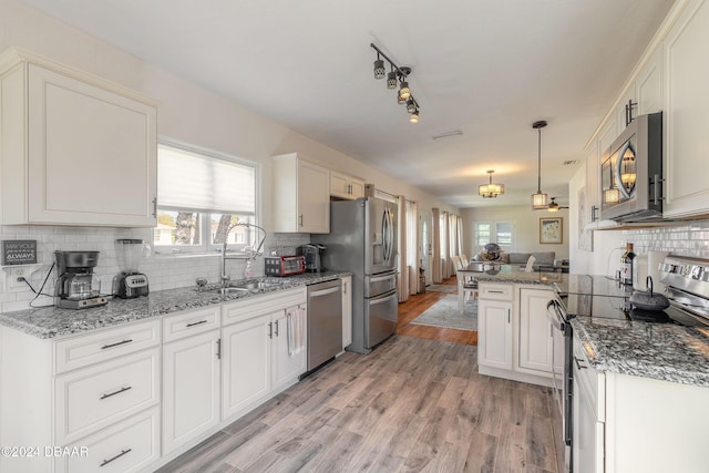 kitchen with white cabinetry, sink, kitchen peninsula, and stainless steel appliances