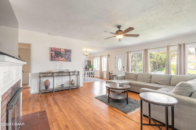 living room with ceiling fan, a healthy amount of sunlight, a textured ceiling, and light hardwood / wood-style flooring