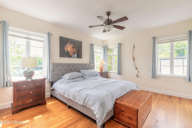 bedroom featuring ceiling fan, light hardwood / wood-style floors, and multiple windows