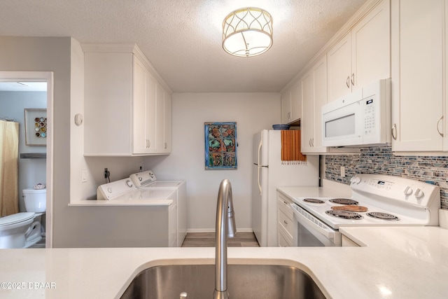 kitchen with sink, white appliances, white cabinets, independent washer and dryer, and backsplash