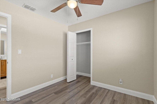 unfurnished bedroom featuring ceiling fan, a textured ceiling, a closet, and light wood-type flooring