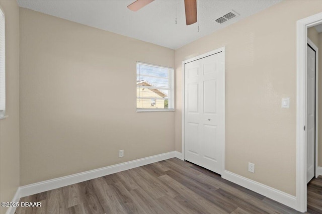 unfurnished bedroom featuring hardwood / wood-style flooring, ceiling fan, and a closet