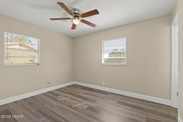 unfurnished room with ceiling fan, a healthy amount of sunlight, wood-type flooring, and a textured ceiling