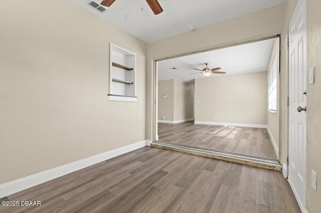 spare room with ceiling fan, wood-type flooring, and built in features