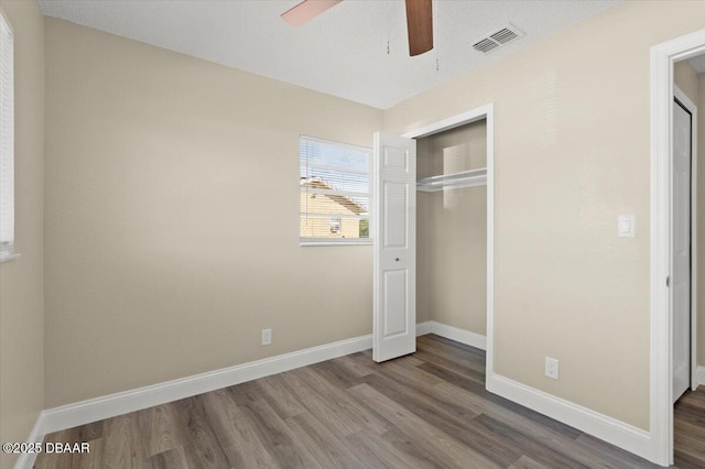 unfurnished bedroom featuring hardwood / wood-style floors, ceiling fan, and a closet