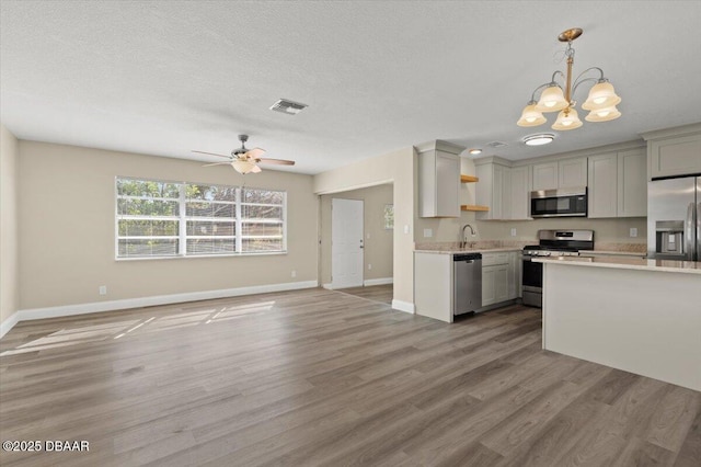 kitchen featuring stainless steel appliances, hardwood / wood-style floors, pendant lighting, and a textured ceiling