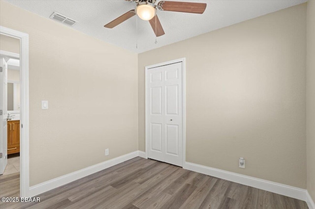 unfurnished bedroom featuring a textured ceiling, light hardwood / wood-style floors, a closet, and ceiling fan