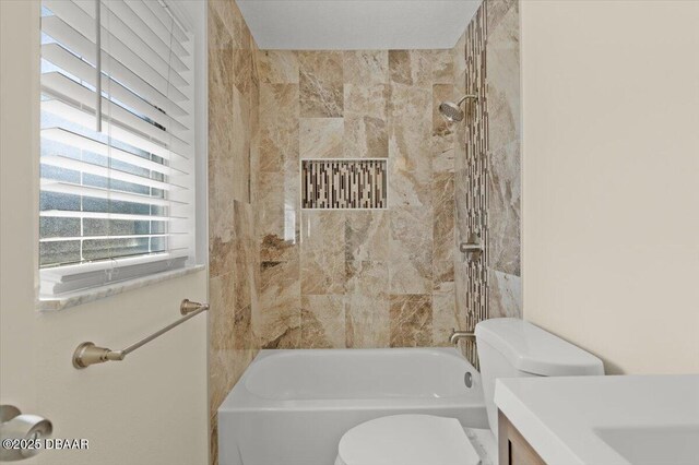 full bathroom featuring vanity, tiled shower / bath, and toilet