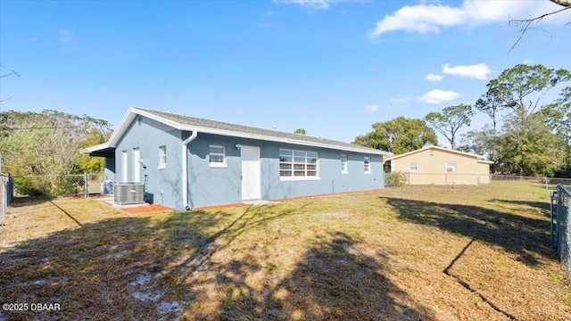 back of property with central AC unit and a lawn