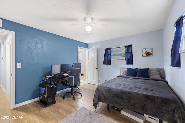 bedroom with hardwood / wood-style flooring, ceiling fan, and a textured ceiling