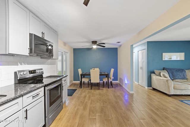 kitchen with stainless steel appliances, dark stone counters, light hardwood / wood-style flooring, and white cabinets