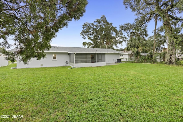 back of property with central AC unit, a lawn, and a sunroom