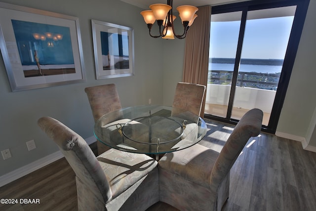 dining room with dark hardwood / wood-style flooring, a water view, and a chandelier