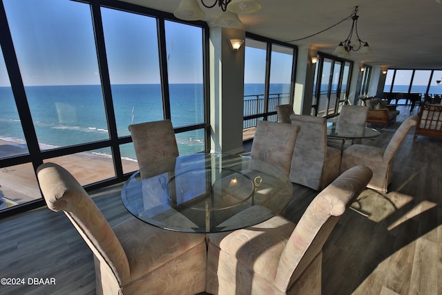 dining space with expansive windows, hardwood / wood-style flooring, a water view, and a notable chandelier