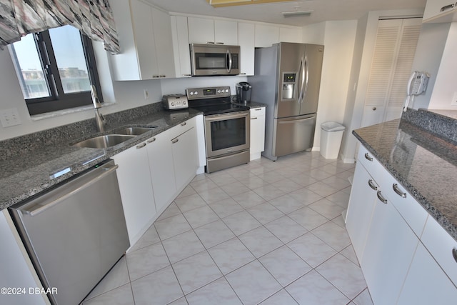 kitchen with stainless steel appliances, dark stone countertops, and white cabinetry