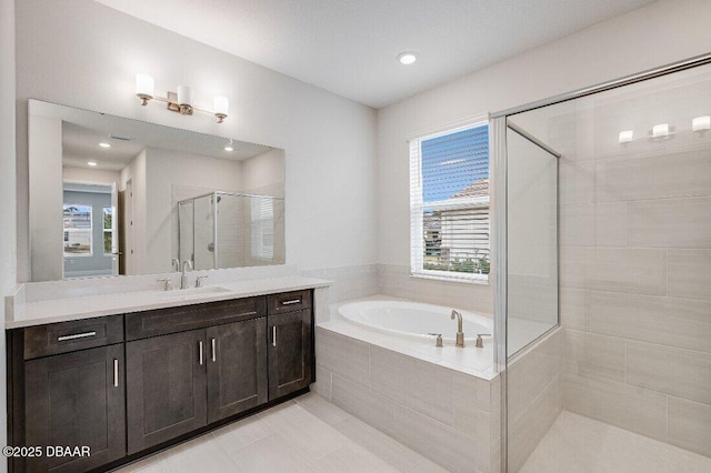 bathroom featuring independent shower and bath, vanity, and a healthy amount of sunlight