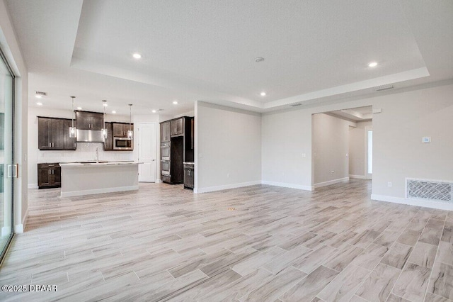 unfurnished living room featuring light hardwood / wood-style floors and a tray ceiling