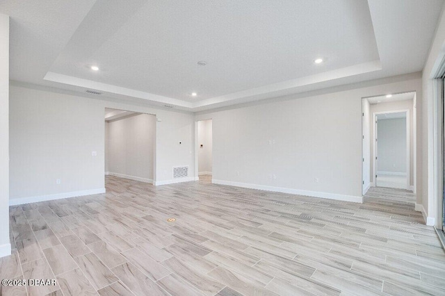 spare room with a raised ceiling and light wood-type flooring