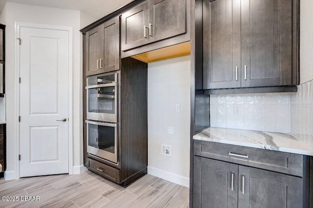 kitchen with light stone countertops, dark brown cabinets, and stainless steel double oven