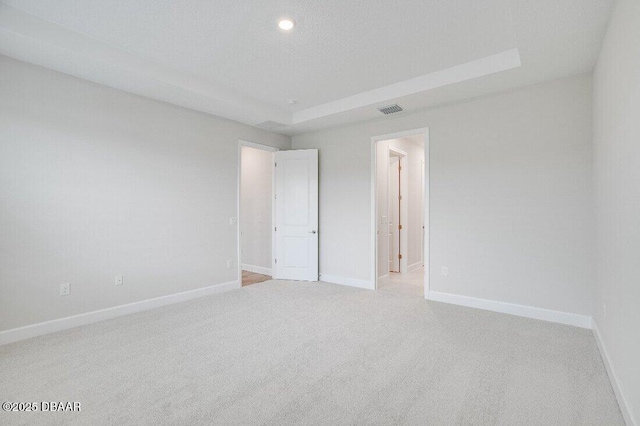 carpeted spare room featuring a tray ceiling