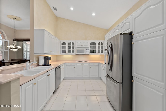 kitchen featuring white cabinetry, sink, hanging light fixtures, stainless steel appliances, and vaulted ceiling