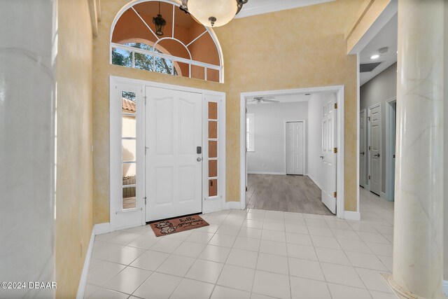 tiled entryway with ceiling fan and a towering ceiling