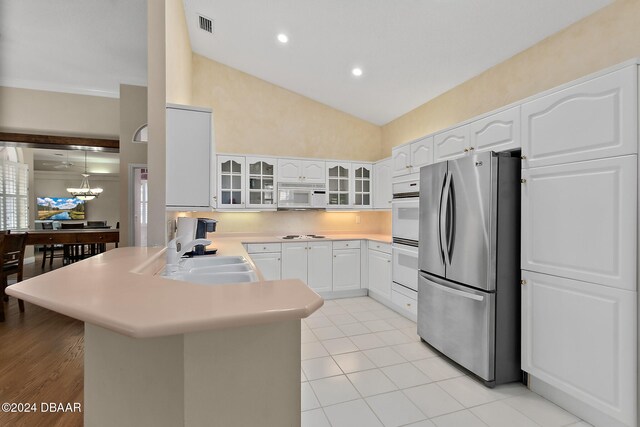 kitchen with sink, an inviting chandelier, pendant lighting, white appliances, and white cabinets