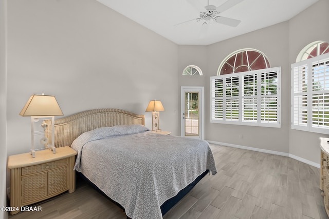 bedroom with hardwood / wood-style floors, ceiling fan, and a high ceiling