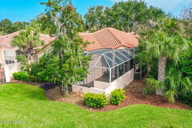 back of property with glass enclosure and a lawn