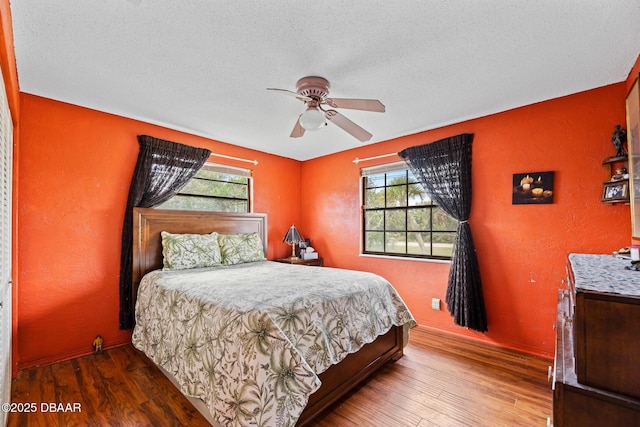 bedroom with ceiling fan, multiple windows, and wood-type flooring