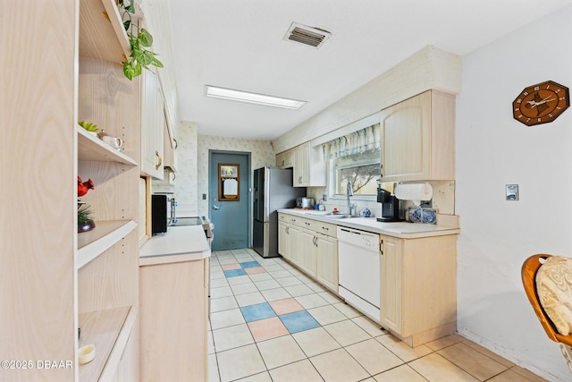 kitchen featuring stainless steel refrigerator with ice dispenser, light tile patterned floors, dishwasher, and sink