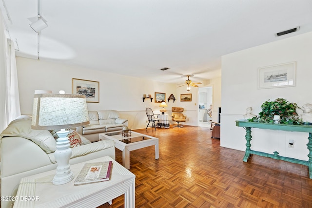 living room featuring ceiling fan and dark parquet flooring