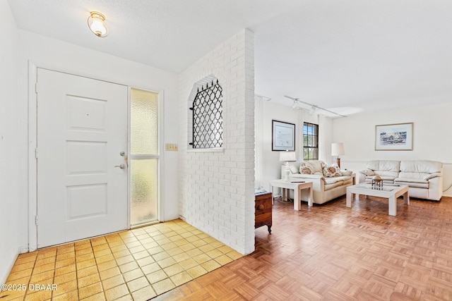 foyer featuring a textured ceiling, light parquet floors, and rail lighting