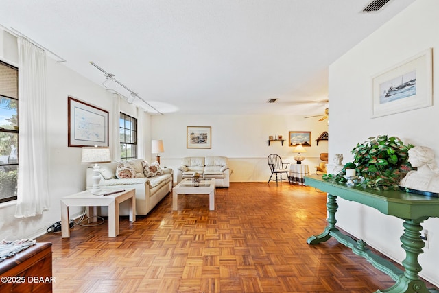 living room with ceiling fan, light parquet flooring, and track lighting