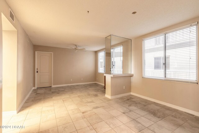 spare room featuring a ceiling fan, baseboards, and light tile patterned floors
