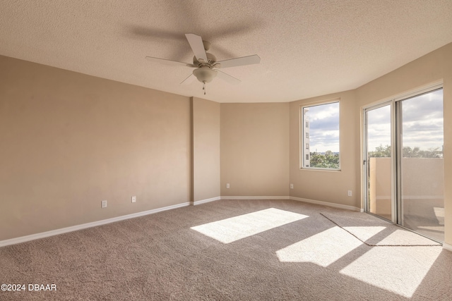 empty room with ceiling fan, light colored carpet, and a textured ceiling