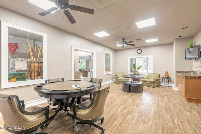 dining area with a paneled ceiling, light hardwood / wood-style floors, and a wealth of natural light