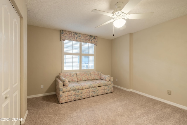 sitting room featuring carpet, ceiling fan, and a textured ceiling