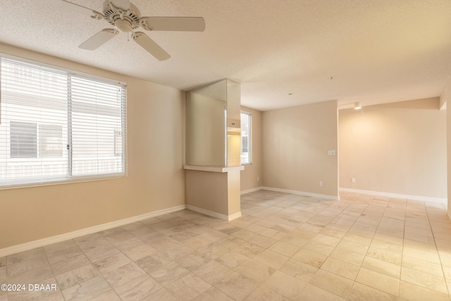 spare room featuring ceiling fan, a healthy amount of sunlight, and a textured ceiling