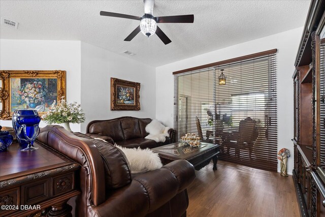 living room with dark hardwood / wood-style floors, ceiling fan, and a textured ceiling