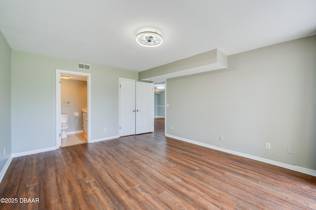 944 S Peninsula Dr Unit 104, Daytona Beach, FL 32118 - unfurnished bedroom with wood finished floors, baseboards, and ensuite bathroom