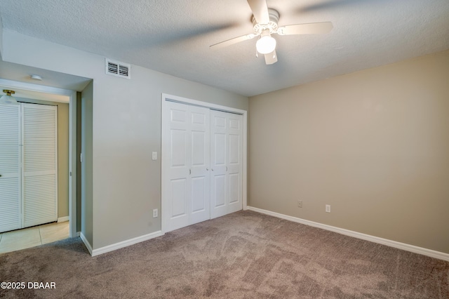 944 S Peninsula Dr Unit 104, Daytona Beach, FL 32118 - unfurnished bedroom with light colored carpet, a closet, baseboards, ceiling fan, and a textured ceiling
