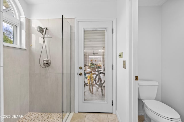 bathroom featuring tile patterned floors, toilet, and a tile shower