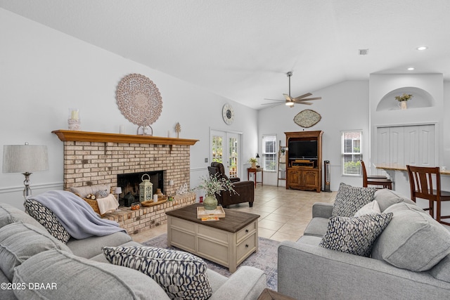 tiled living room with ceiling fan, high vaulted ceiling, and a fireplace