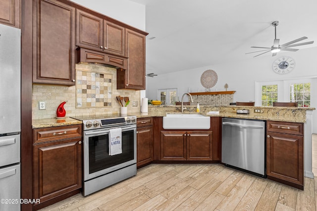 kitchen with sink, light hardwood / wood-style floors, kitchen peninsula, and appliances with stainless steel finishes