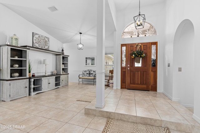 foyer entrance with light tile patterned flooring, high vaulted ceiling, and an inviting chandelier