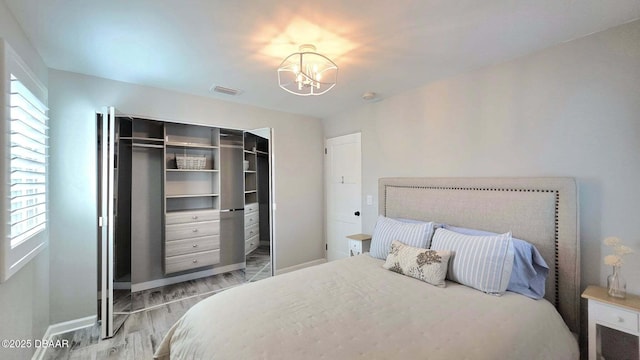 70 Ocean Shore Dr, Ormond Beach, FL 32176 - bedroom with light wood-style flooring, a chandelier, a closet, and baseboards