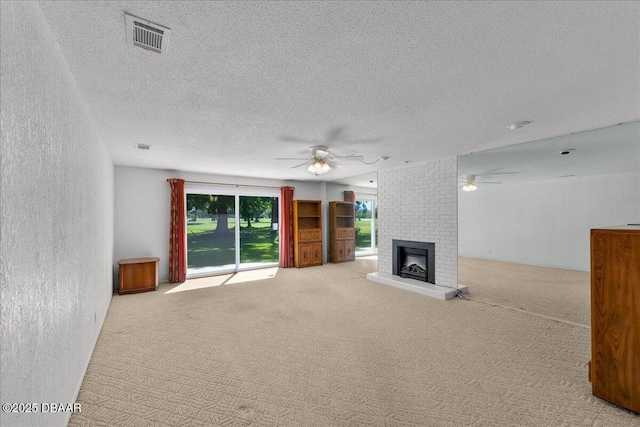 unfurnished living room featuring a textured ceiling, a fireplace, light colored carpet, and ceiling fan