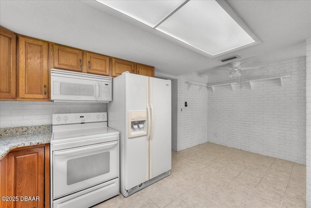 kitchen featuring white appliances, ceiling fan, and brick wall