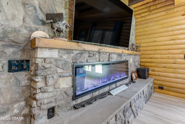 interior details with a stone fireplace, wood finished floors, and log walls